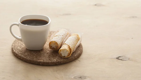 Sött mellanmål med kaffe och våffelrör på trä bakgrund — Stockfoto