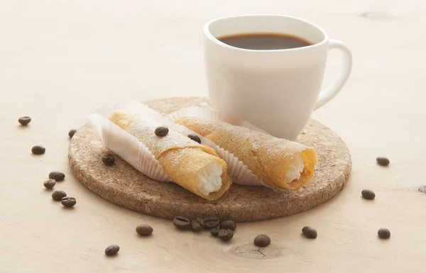 Sweet snack with coffee and waffle tubes on wood background — Stock Photo, Image