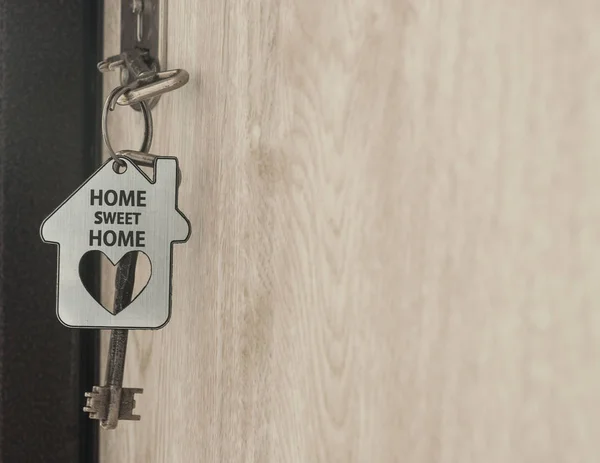 House key on a house shaped silver keyring in the lock of a door — Stock Photo, Image