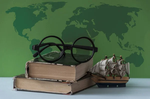 Book, vintage okulary, model statku morskiego i mapa na kolorowe backgr — Zdjęcie stockowe
