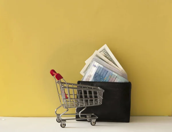 Cartera con dinero, carrito de compras sobre fondo colorido. Espacio f — Foto de Stock