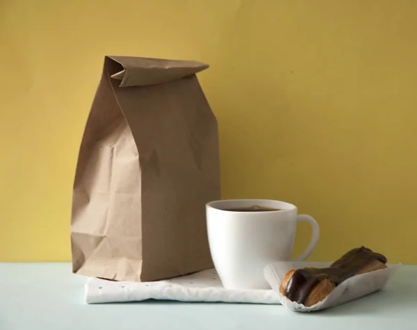 Blank brown paper bag and white coffee cup with chocolate cookie — Stock Photo, Image