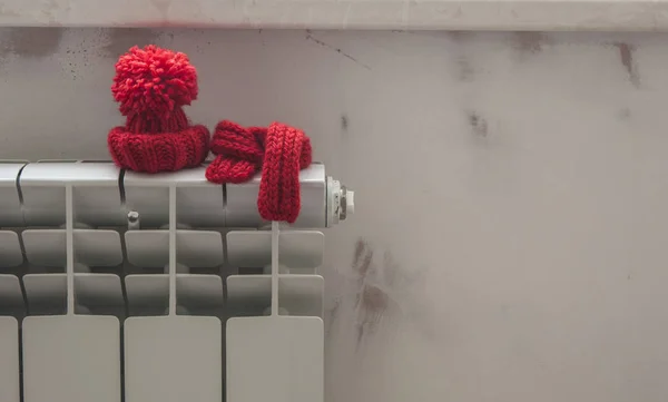 Hausmodell mit roter Strickmütze und Schal auf Heizkörper. — Stockfoto