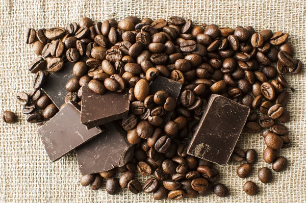 Čokoládové a kávové fazole na textilním pozadí — Stock fotografie