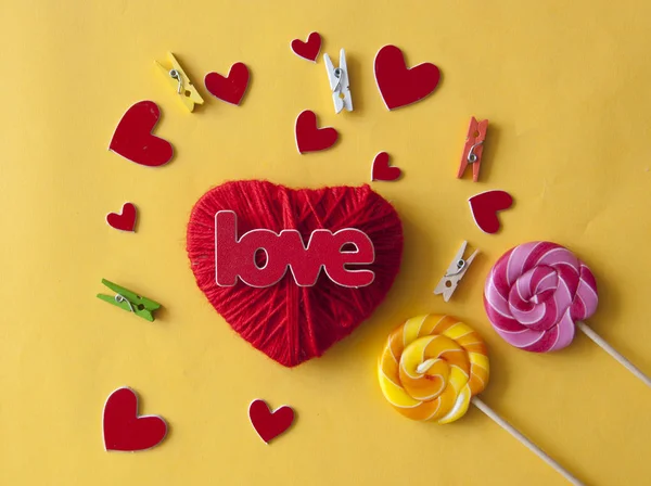 Amor palabra, corazón y caramelos lollipop sobre fondo de papel amarillo —  Fotos de Stock