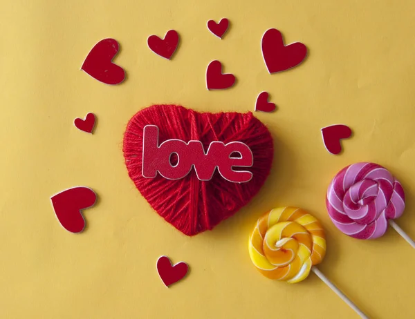 Amor palabra, corazón y caramelos lollipop sobre fondo de papel amarillo —  Fotos de Stock