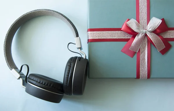 Music concept with gift box and headphones on blue paper backgro