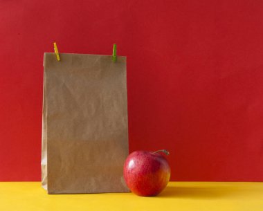 Kahverengi kağıt torba ve renkli kağıtta kırmızı elma.
