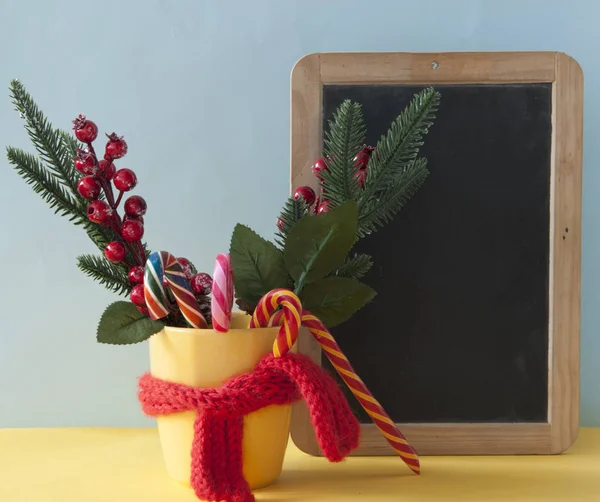 Weihnachtsbonbons Zuckerstangen im gelben Becher mit Beeren Stechpalme Zweige — Stockfoto