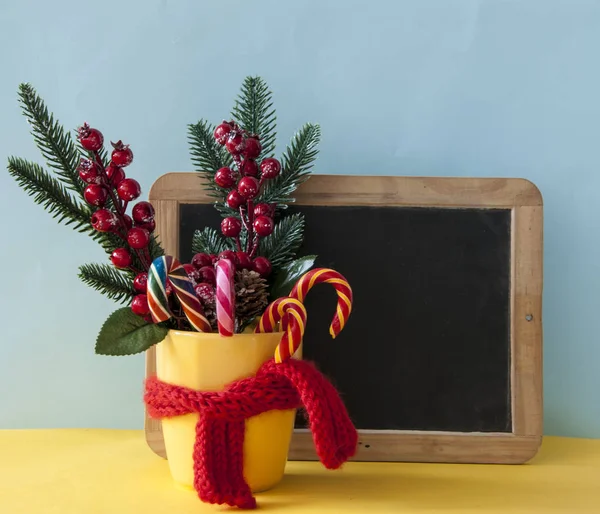 Julgodis käppar i gul mugg med bär järnek grenar — Stockfoto