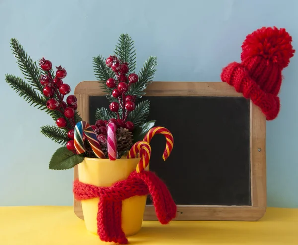 Julgodis käppar i gul mugg med bär järnek grenar — Stockfoto