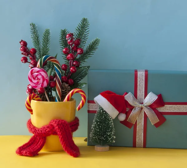 Weihnachtsbonbons Zuckerstangen im gelben Becher mit Beeren Stechpalme Zweige — Stockfoto