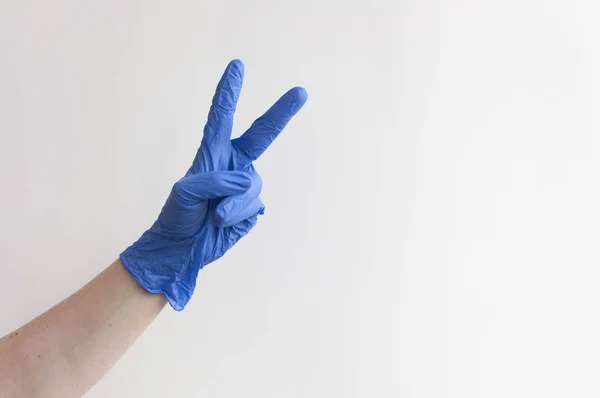 Hand i blå handskar underteckna seger — Stockfoto