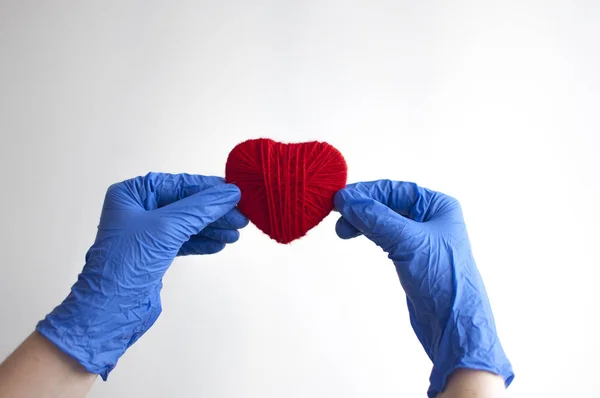 Una mano in un guanto blu tiene un cuore rosso. Concetto medico. Copia — Foto Stock