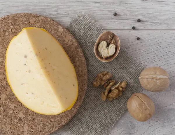 Slice cheese with walnuts on wooden background — ストック写真