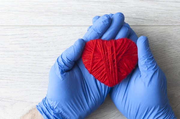 A hand in a blue glove holds a red heart. Medical concept. Copy — ストック写真