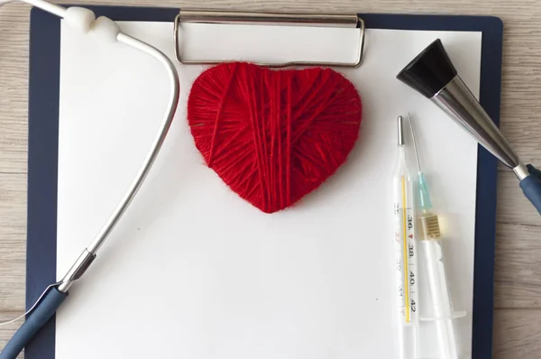 Medical stethoscope and a red heart and tablet placed on a docum — ストック写真