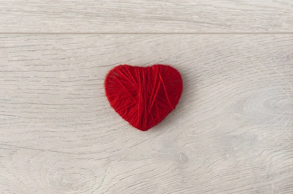 Ahşap arka planda iplikten yapılmış kırmızı kalp — Stok fotoğraf