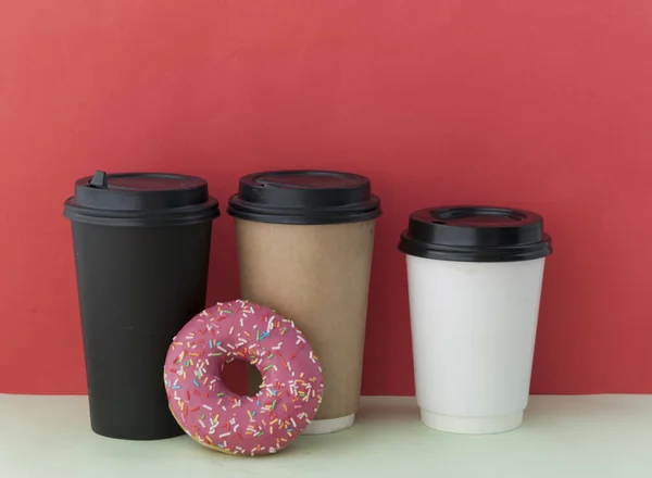 Beignet rond glacé rouge et tasse en papier avec café — Photo