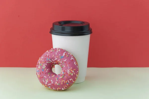 Beignet rond glacé rouge et tasse en papier avec café — Photo