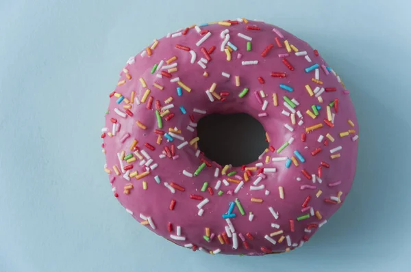 Een roze zoete donut met blauwe achtergrond — Stockfoto