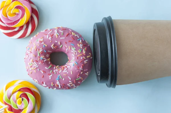 Beignet rond glacé rouge et tasse en papier avec café — Photo