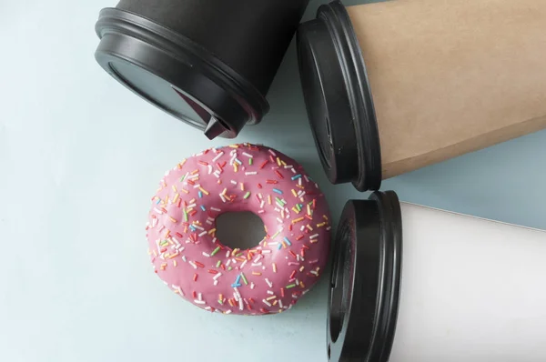 Beignet rond glacé rouge et tasse en papier avec café — Photo