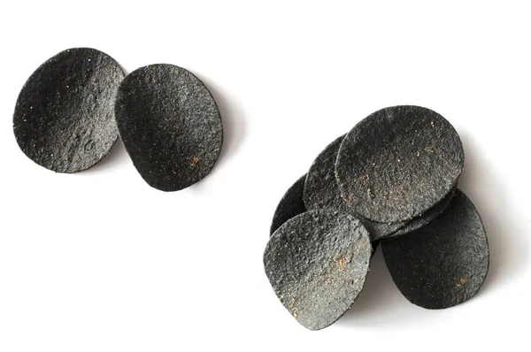 Pile black potato chips on white background. Top view — Stock Photo, Image