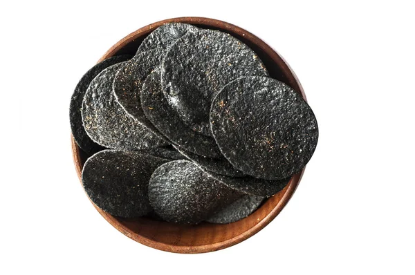 Pile black potato chips in wooden bowl on white background. Top — Stock Photo, Image