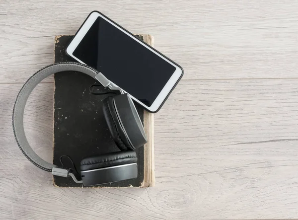 Cuffie, smartphone e libro bianco aperto su tavolo in legno. Inizio pagina — Foto Stock