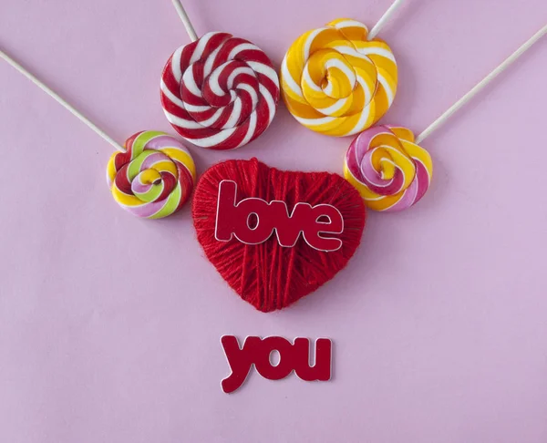 Love word, heart and lollipop candies on pink paper background. — Stock Photo, Image