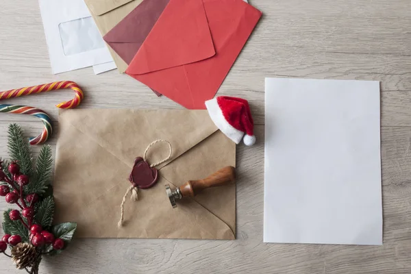 Пустой конверт с белой пустой бумагой и красной шляпой Санты на свету — стоковое фото