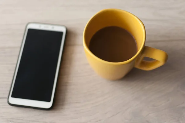 Kaffeetasse und Smartphone auf Holztisch. Blick von oben — Stockfoto