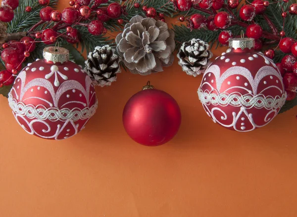 Bolas de Navidad, bayas y conos con espacio de copia sobre papel rojo — Foto de Stock