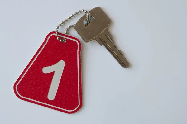 Fecho de uma chave do quarto número 1 com a chave em um papel de fundo — Fotografia de Stock