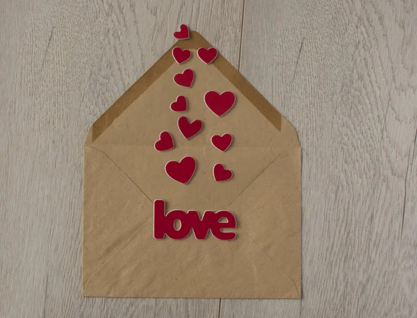 Brązowa koperta koloru i słowo "miłość" z uszczelką woskową na białym drewnie — Zdjęcie stockowe