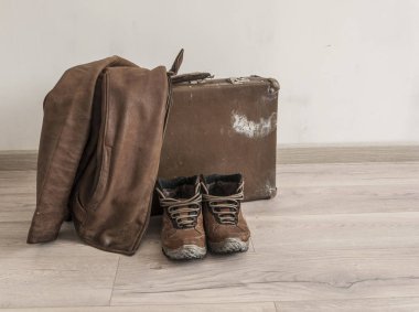 Erkek ayakkabıları ve tahta döşeme üzerinde deri ceketi olan eski çanta.