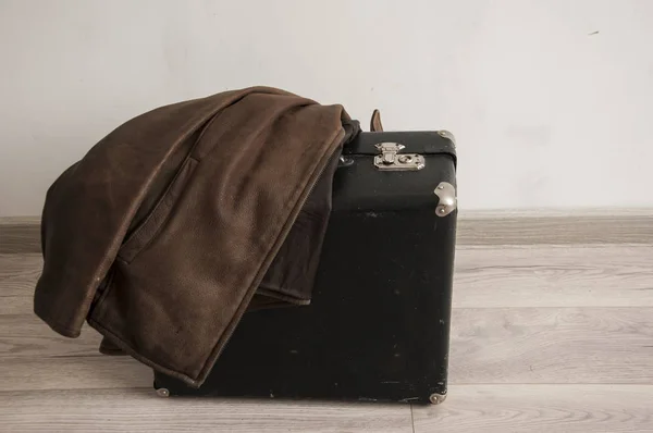 Кожаная куртка на старом чемодане в комнате с белым — стоковое фото
