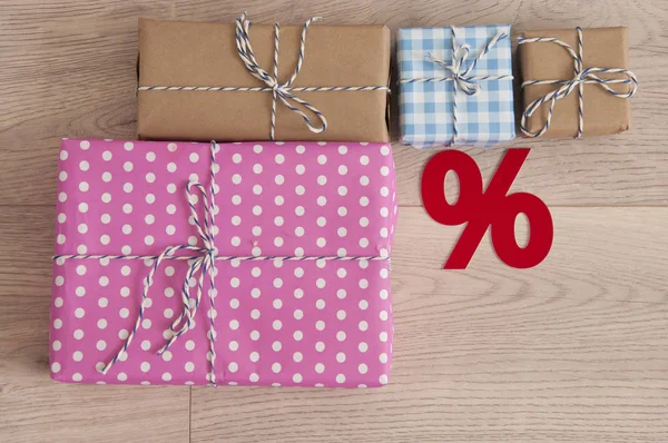Segno percentuale e scatola regalo colorata sul pavimento in legno all'interno ba — Foto Stock