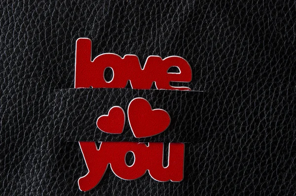 Palavra Amor com corações vermelhos sobre fundo de couro preto. Saudação — Fotografia de Stock