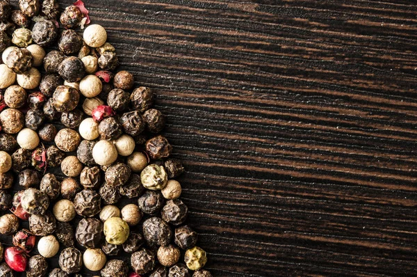 Spice allspice red, black and white peas on dark wooden table — 스톡 사진