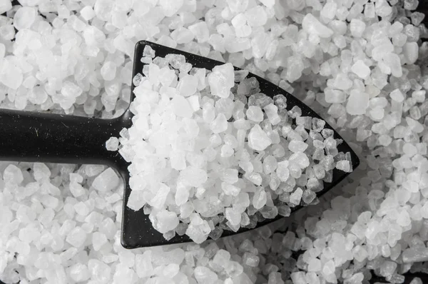 Mořská sůl v černé lopatě na kuchyňském stole. pohled shora — Stock fotografie