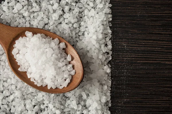 Tengeri só fából készült kanállal a konyhaasztalon. felülnézet — Stock Fotó