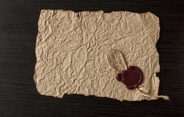 Old paper with seal wax on black wooden background — ストック写真
