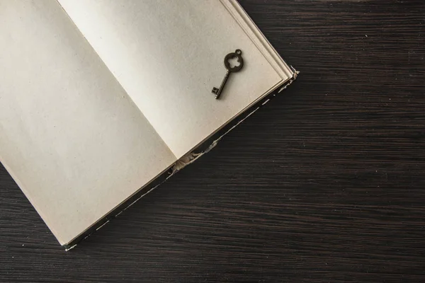 Prázdné otevřít starou knihu a klíč na tmavém starém dřevěném stole — Stock fotografie