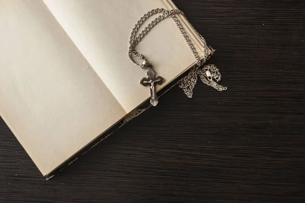 Detailní záběr křesťanského kříže se stříbrným řetízkem na prázdné otevřené knize — Stock fotografie