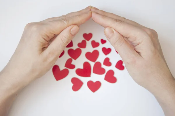 Valentijnsdag achtergrond. Vrouwen handen houden veel rode harten vast. — Stockfoto