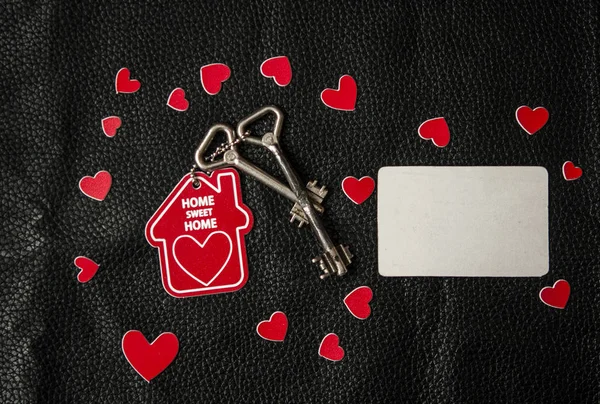 Klein huis en een sleutel met een sleutelhanger in de vorm van een hart — Stockfoto