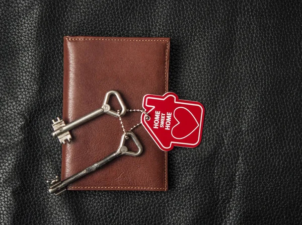 Brown leather wallet with home key on black background. Top view — Stock Photo, Image