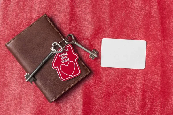 Коричневый кожаный бумажник с ключом от дома на красном фоне. Вид сверху , — стоковое фото